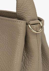 Svijetlosiva, teksturirana kožna torba s zlatnim okruglim detaljem, koja ima mekani, strukturirani oblik i vidljive šavove.