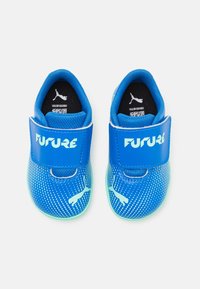 Blue sports shoes with a mesh design, featuring a Velcro strap and light blue accents, including a Puma logo. Soft sole for comfort.