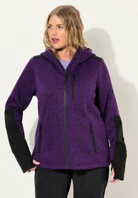 Giacca in pile viola con chiusura a zip, pannelli neri a contrasto, maniche lunghe e cappuccio. Presenta tasche laterali e una tasca sul petto con zip.