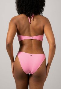 Rosa bikini-set med en bandeau-topp med justerbara remmar och matchande låghöga bottnar. Slät textur med minimala hårdvaruaccenter.