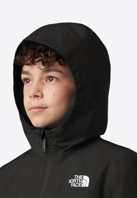 Černá voděodolná bunda s kapucí a předním zipem s bílým logem. Hladká struktura a střih, který zdůrazňuje funkčnost a teplo.