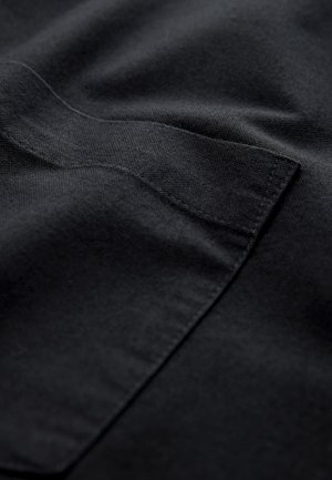 Sort stof med en glat tekstur, med syede kanter og en subtil glans. En lomme er synlig, hvilket tilføjer detaljer til designet.