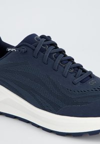 Marineblaue Sportschuhe mit einem strukturierten Mesh-Obermaterial, runden Schnürsenkeln und einer dicken weißen Laufsohle, die eine glatte Oberfläche und subtile Muster aufweist.