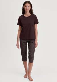 Bordeaux katoenen T-shirt in combinatie met cropped pants met een geometrisch patroon in donkere en lichte kleuren. Eenvoudige, relaxte pasvorm.