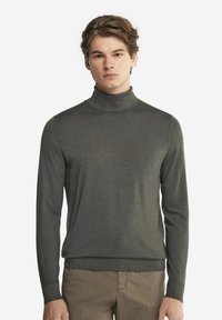 Mörkgrön polotröja i mjukt material, med långa ärmar, en figursydd silhuett och ribbade detaljer vid kragen och nederkanten.