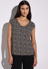 Top de manga corta en negro y crema con un patrón ondulado. Presenta un escote de corte amplio y un ajuste relajado. Textura suave y tela ligera.