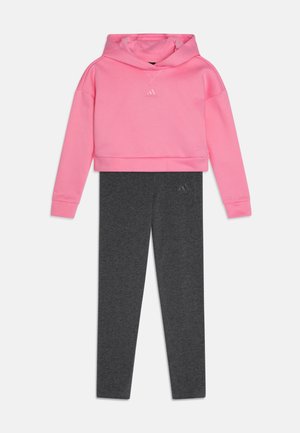 Sudadera recortada rosa con un logo, combinada con leggings gris oscuro; ambos fabricados de una suave mezcla de algodón, que presentan puños acanalados y un corte ajustado.