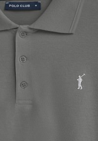 Grå pikétröja i texturerad tyg, med en knäppning med tre knappar och en vit broderad golfare-logotyp på vänster bröst.