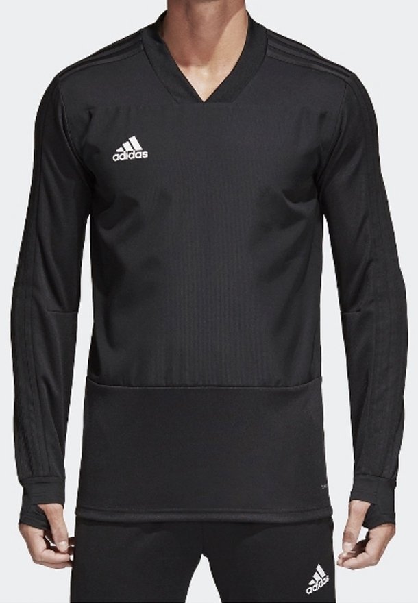 Homme portant un haut de sport à manches longues noir Adidas et un pantalon assorti avec des logos blancs Adidas sur la poitrine et la cuisse.