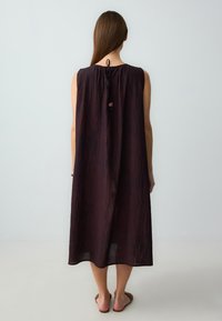 Dunkellila ärmelloses Kleid mit lockerer Passform, runder Ausschnitt, Kordelzug im Rücken und feiner, zerknitterter Textur.