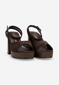 Brown suede platform sandals with a chunky wooden heel, open toe design, and ankle strap featuring a gold buckle.
