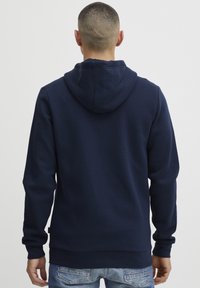 Felpa blu navy con cappuccio foderato, maniche lunghe e orlo dritto. Realizzata in tessuto morbido, presenta un'etichetta sul lato sinistro in basso.