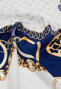 Foulard di seta con sfondo bianco, decorato con motivi di catene dorate e dettagli in blu navy. Il tessuto è morbido e ha una finitura lucida.