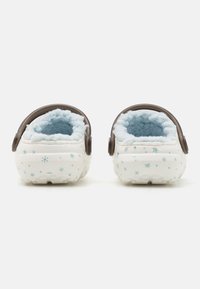 White slipper clogs with blue interior lining and snowflake patterns on the exterior. Features brown back straps and textured soles.
