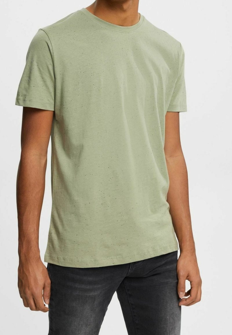T-shirt vert clair à manches courtes en coton doux, avec un col rond classique et une texture subtilement mouchetée sur toute la surface.