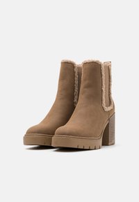 Bottines en suede marron avec une finition texturée, doublure en peluche, panneaux latéraux élastiques et un talon épais avec une semelle striée.