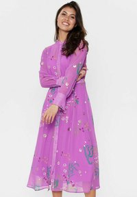 Rochie fluidă, de culoare mov, cu mansete lungi din material transparent, închidere cu nasturi și modele florale în nuanțe de roz, verde și accente metalice.