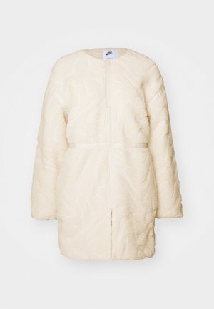 Fehér műszőrme, cipzáros dzseki texturált, absztrakt mintával, hosszú ujjakkal és lekerekített gallérral.