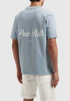 Lichtblauwe katoenen t-shirt met korte mouwen, met witte tekst "Pure Path" en aanvullende tekst op de achterkant. Eenvoudig ontwerp.