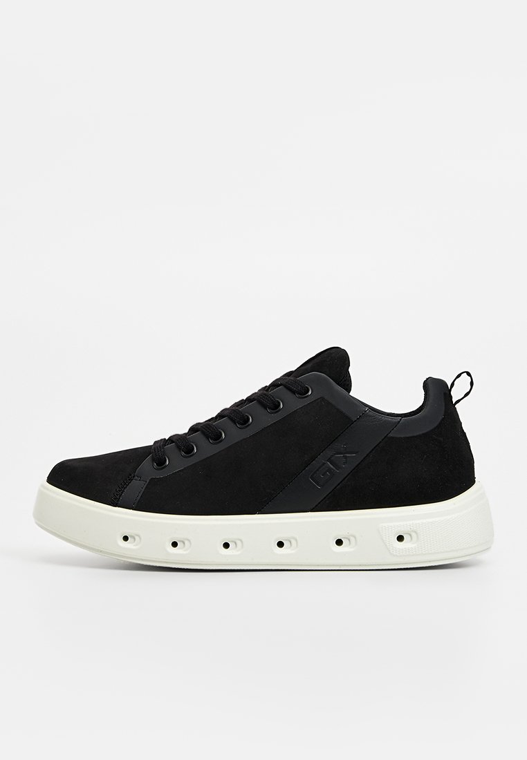 Schwarzer Sneaker mit einem Obermaterial aus Wildleder und einer kontrastierenden weißen Gummisohle. Designed mit sechs Ösen und einer Zuglasche für einfaches An- und Ausziehen.