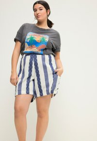 Šedé grafické tričko s designem pláže a krátkými rukávy, kombinované s pruhovanými šortkami v bílé a modré s geometrickými vzory.