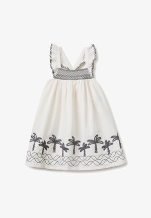 Vestito bianco senza maniche con motivi di palme nere ricamati lungo l'orlo e dettagli di cucitura nera sulle bretelle arricciate e sul petto.