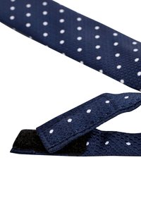 Granatowa taśma materiałowa w białe kropki, charakteryzująca się teksturowaną powierzchnią i zapięciem na rzep, umożliwiającym regulację.