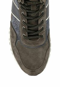 Bruine en blauwe suède sneakers met zwart-witte patroonveters, gestikte details en textuurpanelen aan de zijkant, gezien van bovenaf.