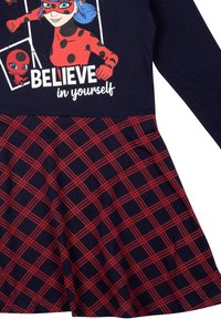 Abito a maniche lunghe con parte superiore blu navy caratterizzata da una grafica e del testo, e una gonna plissettata con un motivo a quadri rosso e blu navy. Tessuto in misto cotone.