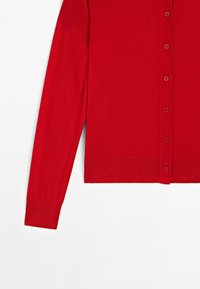 Červený cardigan s kulatým výstřihem, dlouhými rukávy a řadou knoflíků vpředu, položený na bílém pozadí.