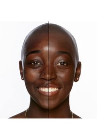 De helft van een vrouwelijk gezicht met een gladde, donkere huid; de andere helft toont een lichtere huidskleur. Beide zijden hebben kort haar en een brede glimlach.