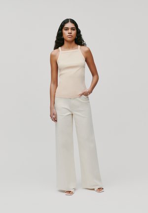 Beige-farbenes, eng anliegendes Tanktop mit breiten Trägern und quadratischem Ausschnitt, kombiniert mit cremefarbenen, weit geschnittenen Hosen. Glatter Stoff mit einem klaren, minimalistischen Design.