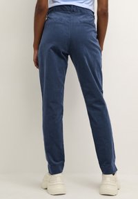 Blauwe corduroy broek met een slim fit, met een middelhoge tailleband en subtiele zakken. Gecombineerd met lichtgekleurde schoenen.