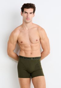 Olivové boxerské trenýrky s čiernym pásom označeným "BJÖRN BORG." Vyrobené z jemného, elastického materiálu, s priliehavým strihom.