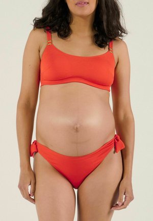 Rotes Bikini-Set mit geripptem Muster, verstellbaren Trägern mit goldenen Akzenten und Bikinihöschen mit seitlicher Bindung. Glatte Stoffoberfläche.