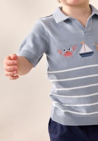 Lyseblå strikket polo med krave, med hvide horisontale striber, broderi af en krabbe og en sejlbåd. Kortærmet, blød tekstur.