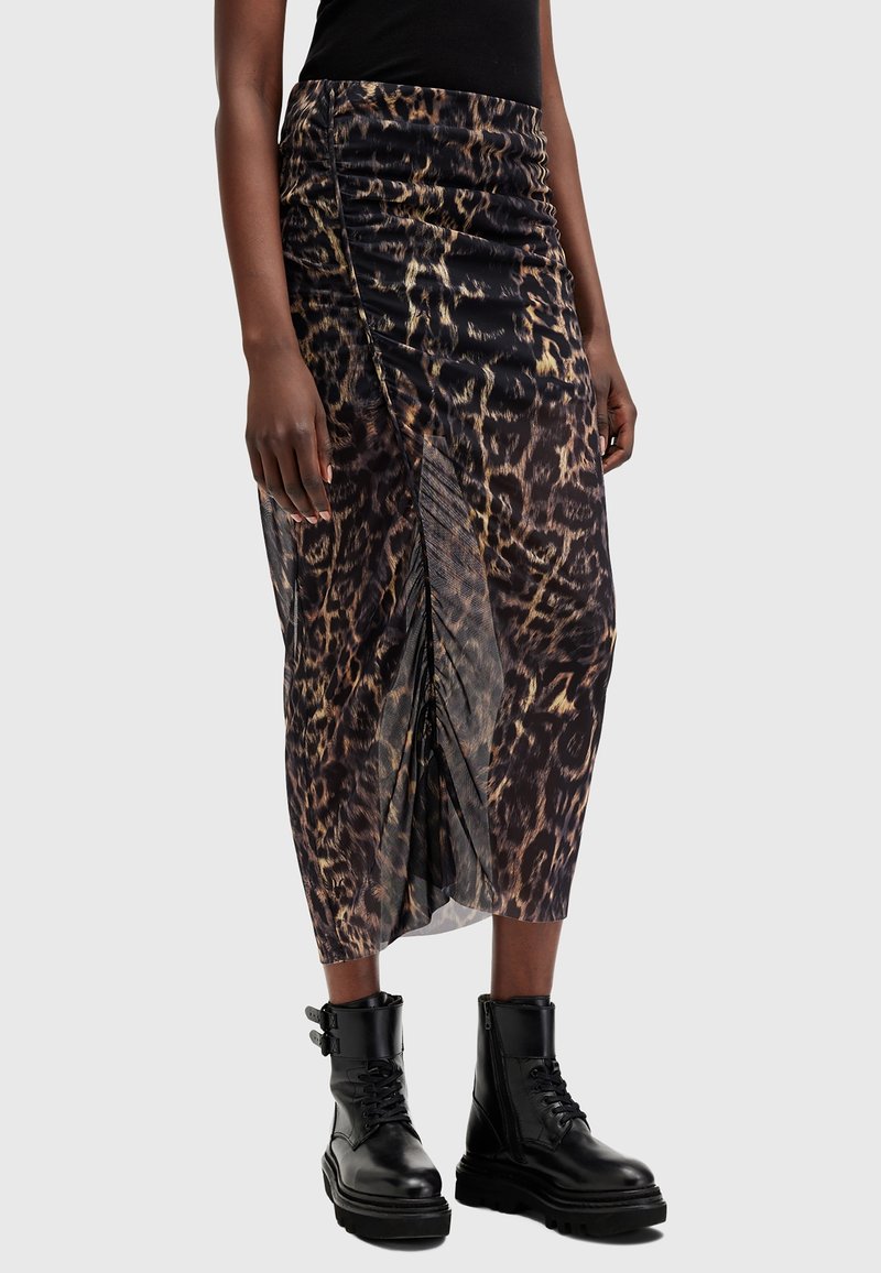 Femme portant une jupe midi taille haute à imprimé léopard avec fronces et des bottes de combat noires à lacets avec boucles latérales.
