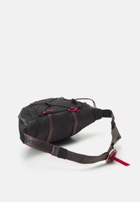 Bolsa de hombro de tela negra con acentos rojos, forma curvada, correa ajustable y cuerdas elásticas externas para aumentar las capacidades de almacenamiento.