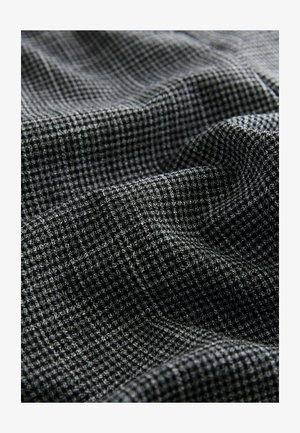 Texturált szövet fekete és szürke kutyafog mintával, enyhén fényes felülettel és puha, leomló tulajdonsággal.