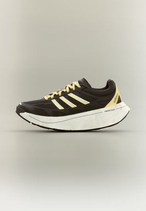 Mørkebrun og gul Adidas løbesko med tyk hvid Swirlfoam-sål og mesh-overdel, vist på neutral baggrund.