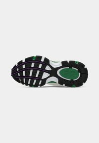 Semelle d’une basket avec un motif en relief noir, blanc, vert et violet, avec le logo Lacoste et un motif de grip texturé sur fond blanc.