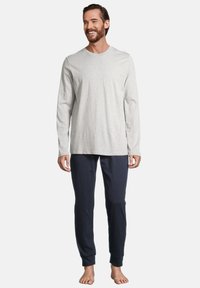 Helles graues Langarmshirt, kombiniert mit marineblauen Hosen, beide aus weichem Stoff, mit entspannter Passform und minimalistischer Gestaltung.