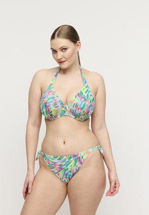 Vrouw die een meerkleurige halterbikini met een tie-dye patroon draagt, poseert tegen een effen witte achtergrond.