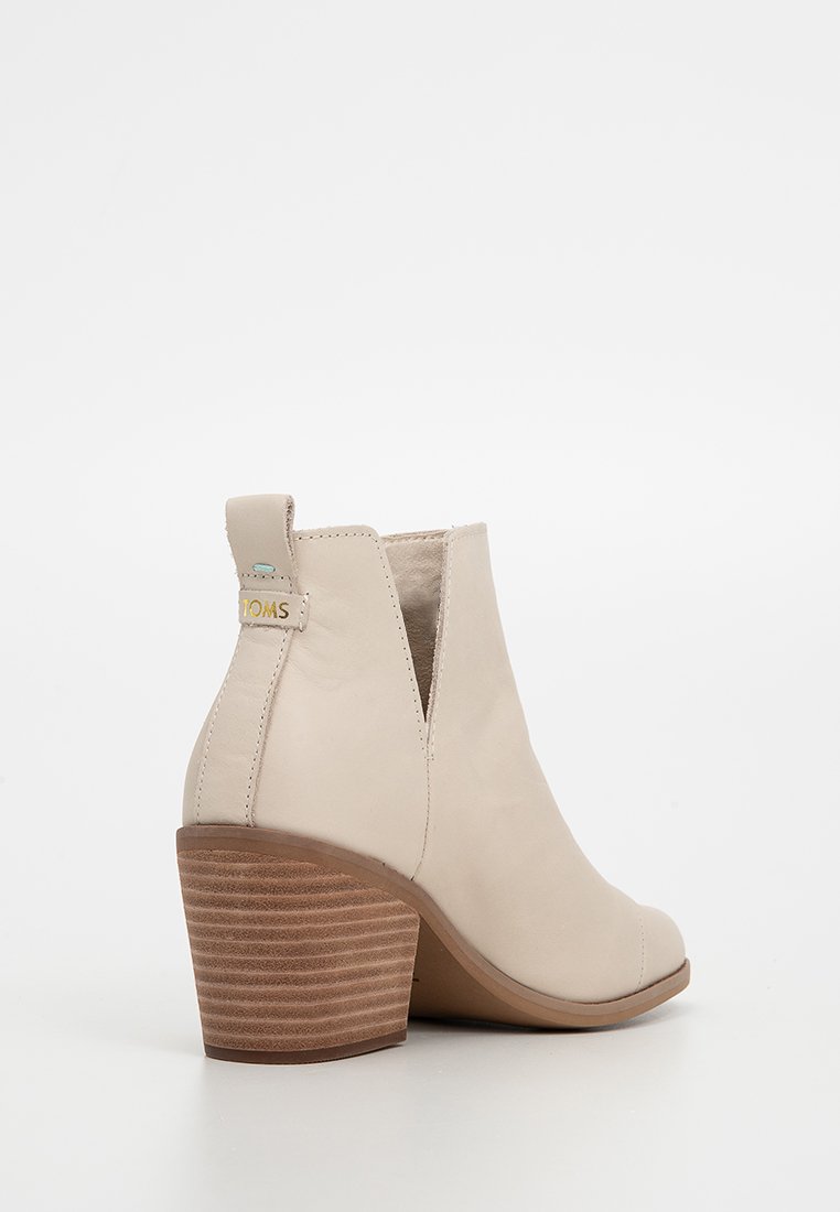 Beige Knöchelstiefel aus glattem Leder. Mit einem gestapelten Holzabsatz und seitlichen elastischen Einsätzen. Das TOMS-Logo ist auf der Rückseite sichtbar.