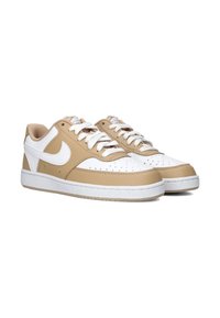 Lichtbruine en witte lage sneakers met een leren afwerking, geperforeerde neus, witte veters en een gestructureerde rubberen zool. Ronde logo aan de zijkant.
