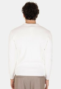 Maglione polo a maniche lunghe bianco a coste con collo tondo, caratterizzato da un tessuto testurizzato e dettagli di cucitura discreti all'orlo e ai polsini.