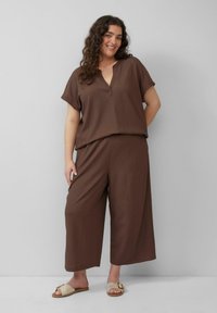 Bruin tweedelig outfit met een loszittende, kortmouwige top met V-hals en wijde broekspijpen. Geweven textuur en ontspannen ontwerp.
