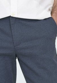 Pantalones textura azul marino con un patrón fino, que presentan un corte relajado, bolsillos laterales y un acabado suave. Adecuados para uso casual.