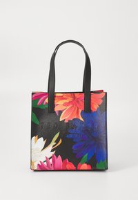 Črna torba z živahnimi cvetličnimi vzorci, ki ima trdne ročaje in vtisnjen ime blagovne znamke "TED BAKER" na sprednji strani.
