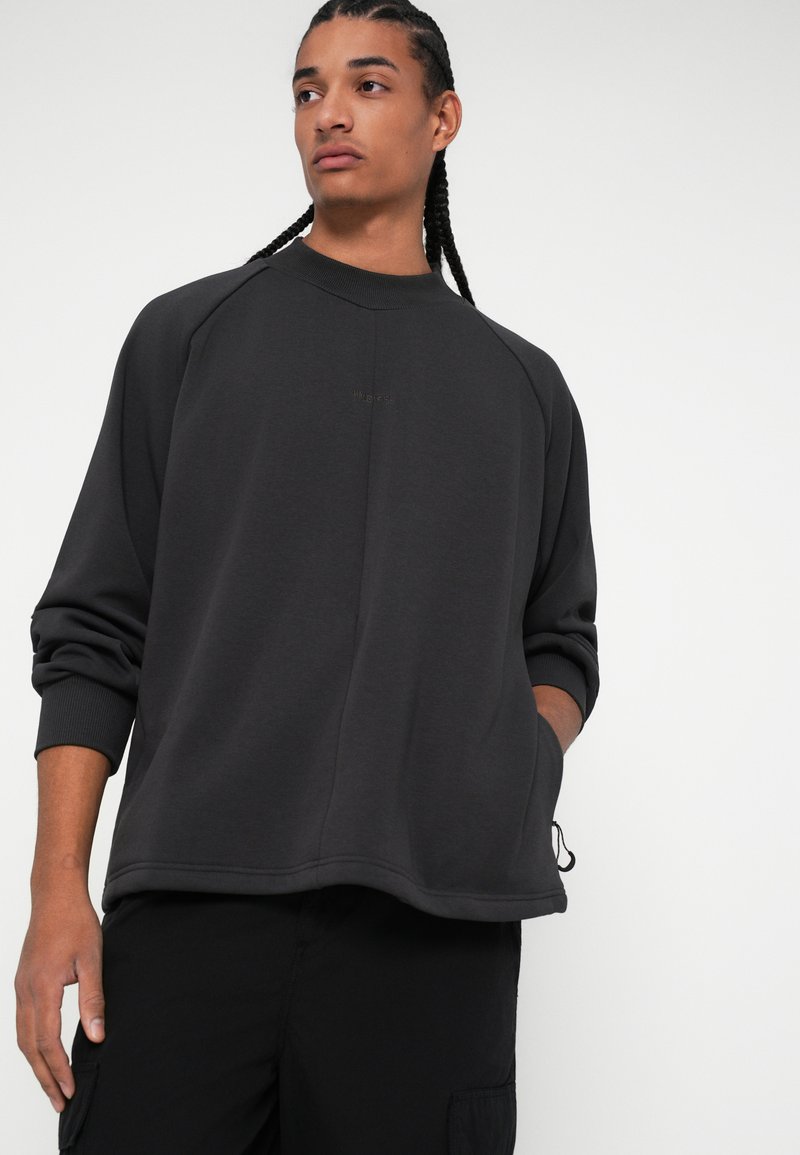 Dunkelgrauer Hoodie mit lockerer Passform, gerippten Bündchen und einem dezenten Logo in der Mitte. Aus weichem, strukturiertem Stoff gefertigt. Lässiges Design.